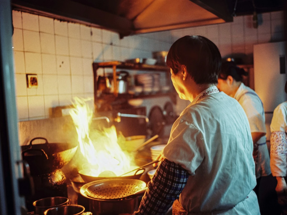 Juru masak di dapur dengan api wajan; foto stok